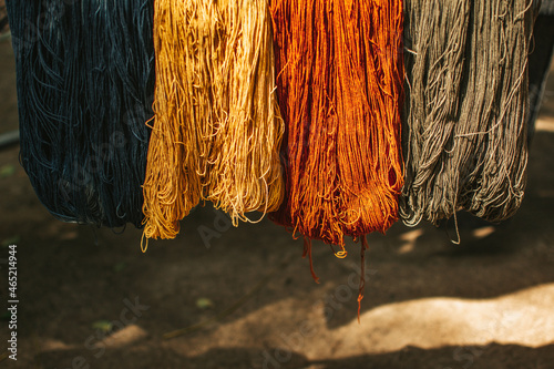 Multi colored threads hanging on bamboo. Hanging skeins of yarn background.
