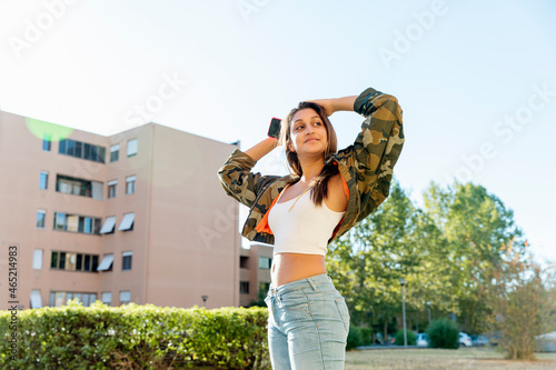 Female teenager with arms raised standing in park