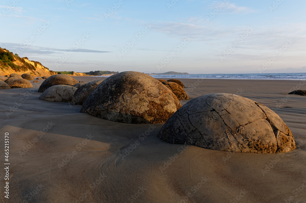 A line of Moeraki Boulders sit on the beach in New Zealand's South Island.
