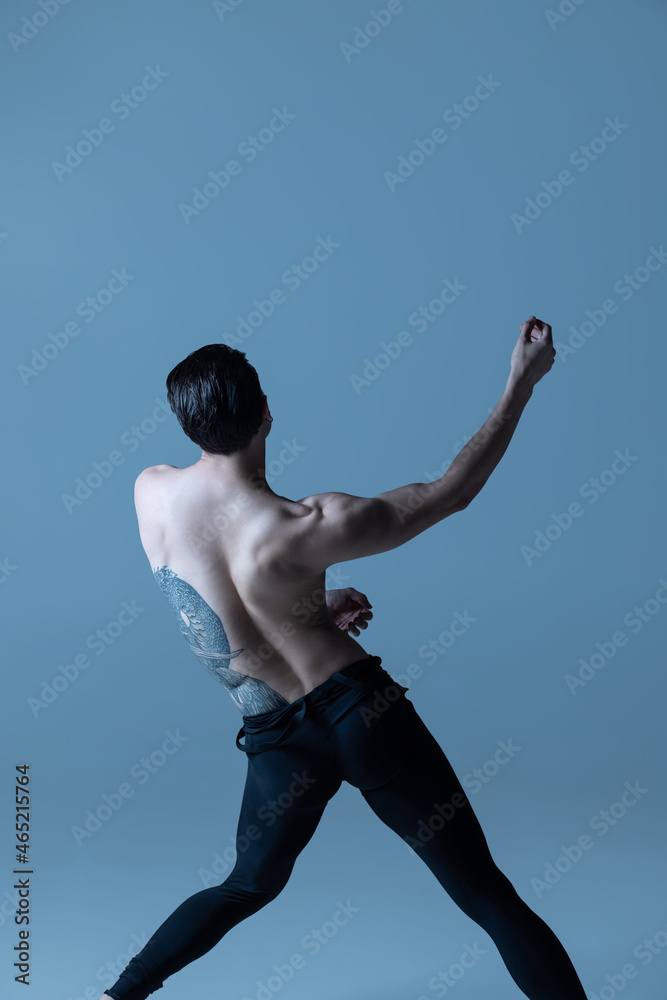 Obraz premium Back view of of young man, flexible male ballet dancer dancing isolated on old navy studio background. Art, motion, inspiration concept.