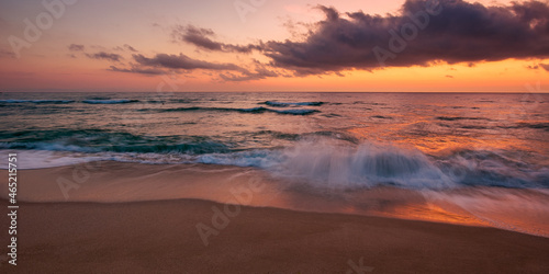 calm sea scenery at dawn. waves wash empty sandy beach at twilight. relax and summer vacation concept. warm velvet season weather with clouds on the sky