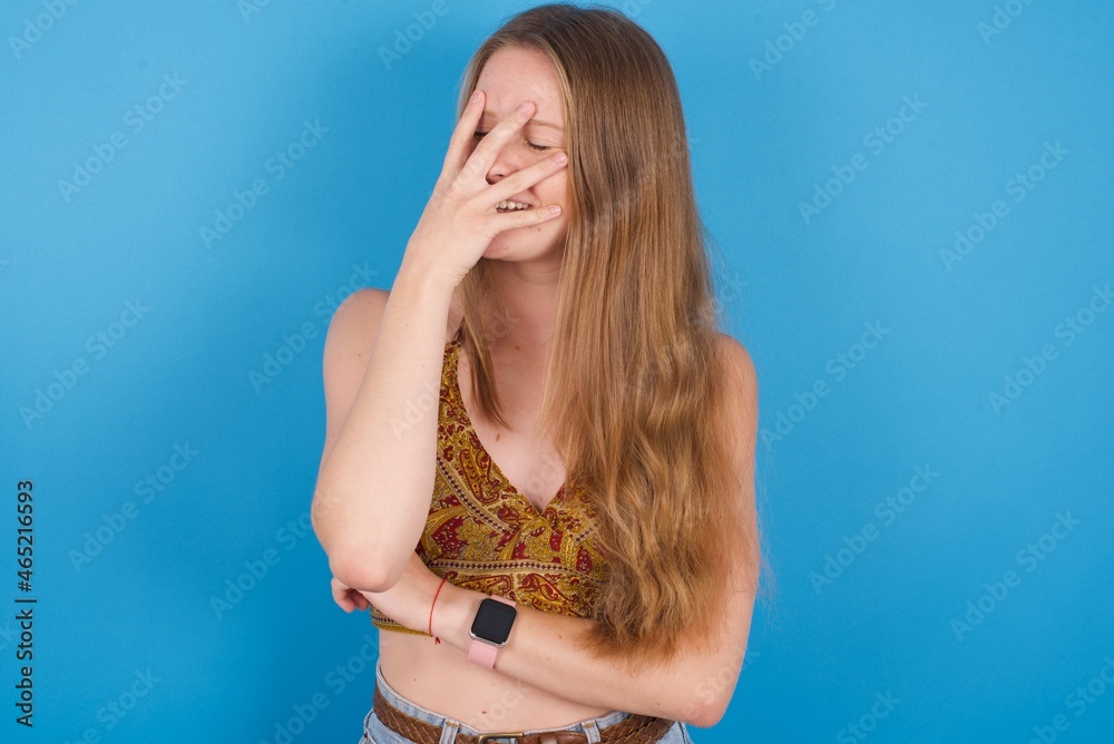 Charismatic carefree joyful young ukranian girl wearing tank top over blue backaground likes laugh out loud not hiding emotions giggling hear funny hilarious joke chuckling facepalm. Charismatic carefree joyful young ukranian girl wearing tank top over blue backaground likes laugh out loud not hiding emotions giggling hear funny hilarious joke chuckling facepalm.