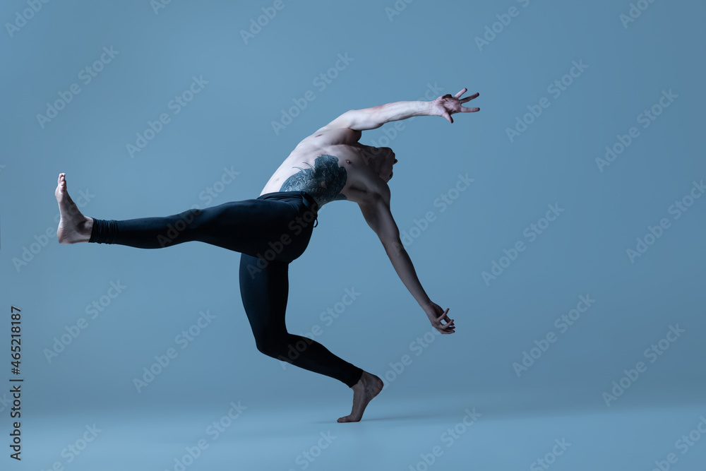 Portrait of young man, flexible male ballet dancer dancing isolated on old navy studio background. Art, motion, inspiration concept. Portrait of young man, flexible male ballet dancer dancing isolated on old navy studio background. Art, motion, inspiration concept.