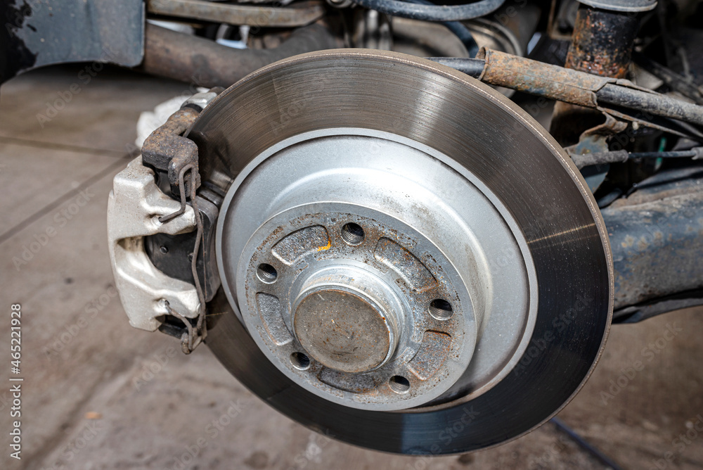 New rear brake calipers and brake discs with pads in a passenger car, on a car jack in the workshop.