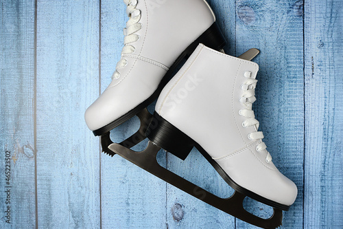 White ice skates for figure skating on a colored wooden surface. Winter sport concept. Top view, flat lay.