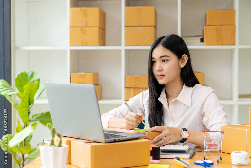 Portrait of a Small Business Startup, SME Owner, Asian Female Entrepreneur Work on receipt boxes and check online orders to prepare the boxes. Selling to customers. Online SME business idea. Portrait of a Small Business Startup, SME Owner, Asian Female Entrepreneur Work on receipt boxes and check online orders to prepare the boxes. Selling to customers. Online SME business idea.