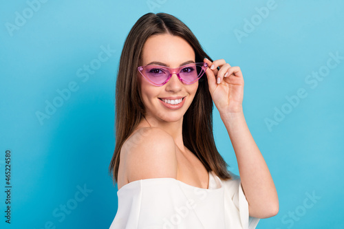 Profile side view portrait of attractive cheerful fashionable girl posing touching specs isolated over bright blue color background