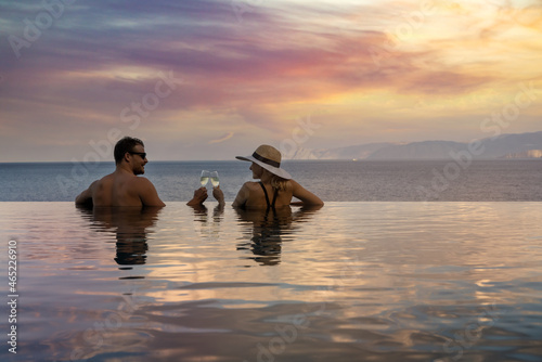 romantic getaways - couple drinking champagne and enjoying beautiful sunset in pool at tropical resort photo