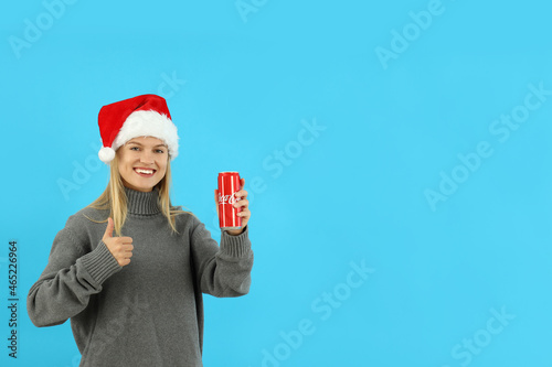 Odessa, Ukraine, 20.10.2021: Attractive girl with can of Coca Cola on blue background