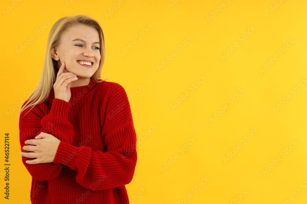 Attractive young woman in red sweater on yellow background Attractive young woman in red sweater on yellow background