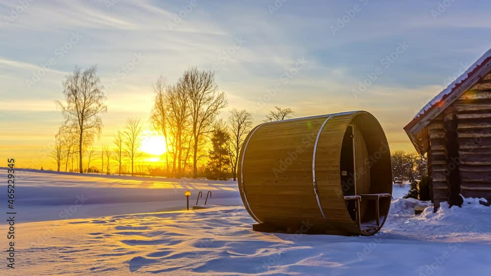 Golden hour sunset at Thermowood barrel sauna outside remote wooden cabin, winter Golden hour sunset at Thermowood barrel sauna outside remote wooden cabin, winter