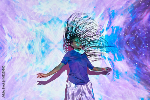 Ethnic woman performing dance in studio with blue and lilac lights