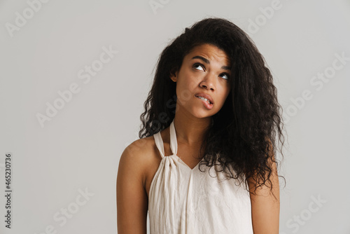 Black young woman in dress biting her lip and looking upward