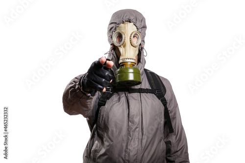 An isolated shot of a man dressed in a gas mask, a jacket with a hood, a backpack, points his index finger into the camera. On a white isolated background