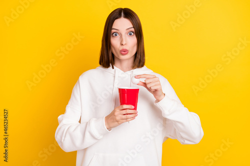 Photo of shocked lady hold alcohol beer cup ping pong ball wear white hoodie isolated yellow color background