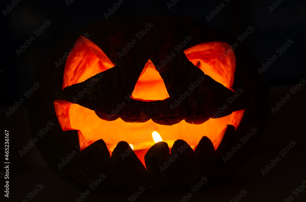 Fototapeta premium old scary smiling glowing pumpkin lantern for halloween in the dark