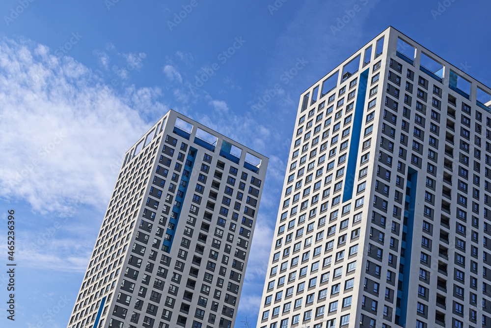 View of modern buildings against a blue sky with white clouds from an unusual angle