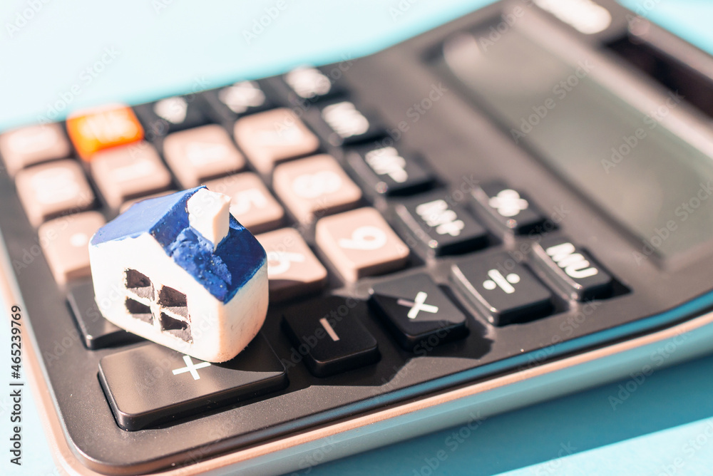 Miniature house calculator. Black blurred calculator.Real estate and mortgage concept.Selective focus,closeup. Miniature house calculator. Black blurred calculator.Real estate and mortgage concept.Selective focus,closeup.