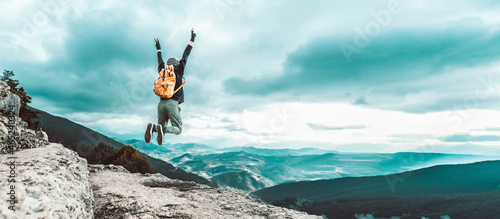 Man traveler on mountain summit enjoying nature view with hands raised over clouds - Sport, travel business and success, leadership and achievement concept