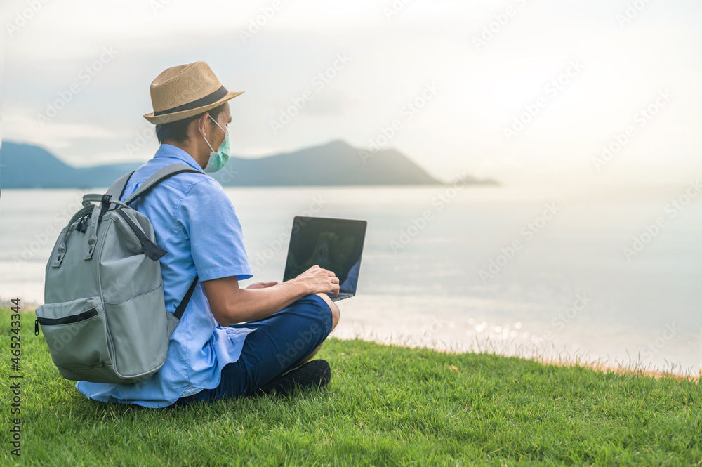 Man wear mask using laptop computer on beach  sea  and Man travel holiday Phuket sandbox Thailand are freedom life financial