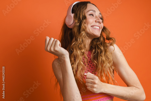 Young ginger woman dancing while listening music with headphones
