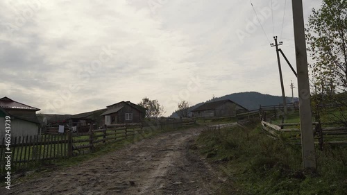 Remote godforsaken village in the mountains in Eastern Europe. Ukrainian rural landscape. Bumpy country road. Mountain field path. Village street with old rustic wooden houses with a mountain view. photo
