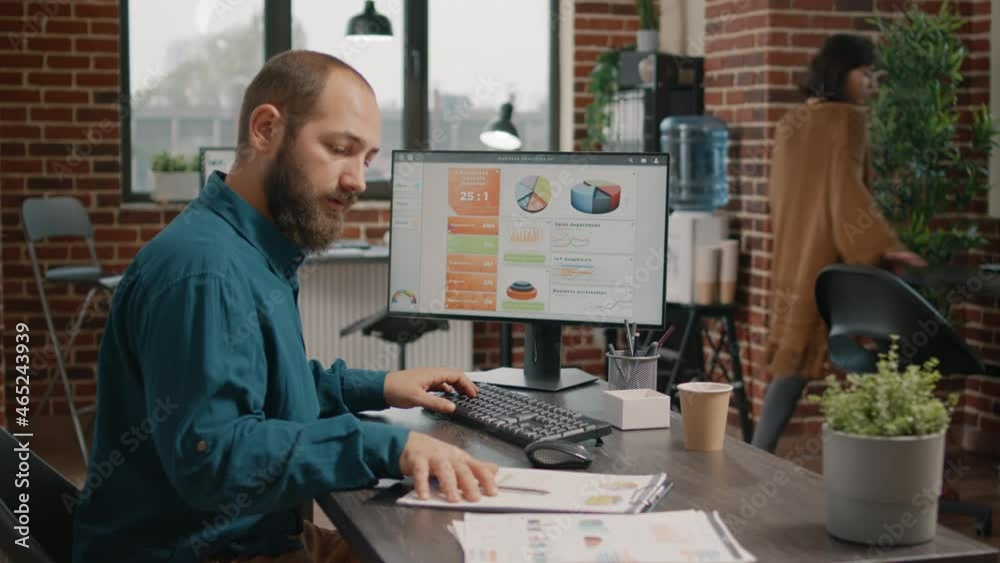 Business man working with data rate charts on computer and papers. Entrepreneur typing on keyboard while analyzing information on files for business project. Research analysis on monitor