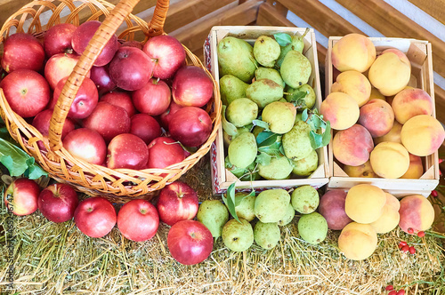  wooden baskets crates full with apples peaches and pears on straw hay bale