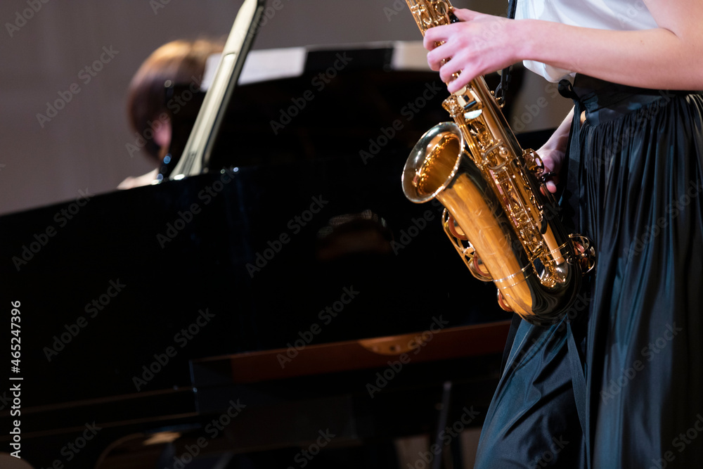 Fototapeta premium A performance of a saxophone player playing together with a pianist on a black grand piano