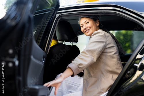 Smiling woman closing taxi door photo