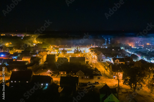 Panorama małego miasteczka Iłowa położonego w Polsce. Jest noc. Ciemności rozświetla światło latarni. Widok z drona.