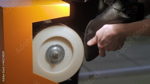 Close up: shoemaker, shoes master using automatic shoe polish machine tool for polishing black leather women footwear at workshop