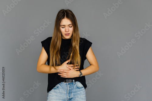 Young pretty woman with stomack pain on gray background photo