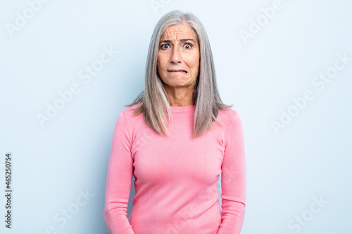 Konstfotografi middle age gray hair woman looking puzzled and confused, biting lip with a nervo