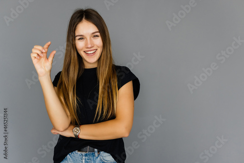 Canvas Print Woman showing small amount of something with fingers, isolated on white backgrou