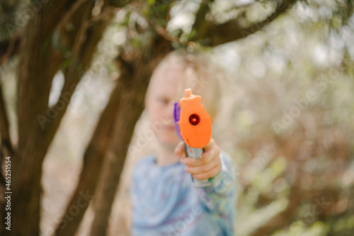 Boy holding toy nerf gun directly in front in backyard battle photo