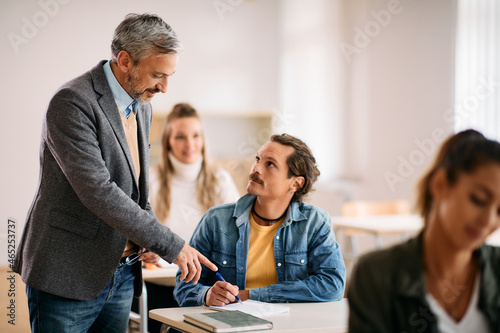 Obraz na plátně Happy professor assists his mid adult student during a class in the classroom