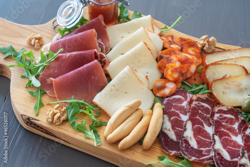Very colorful tapas board of charcuterie with cheese and smoked meats. Decorated with arugula and walnuts. Wine snacks.