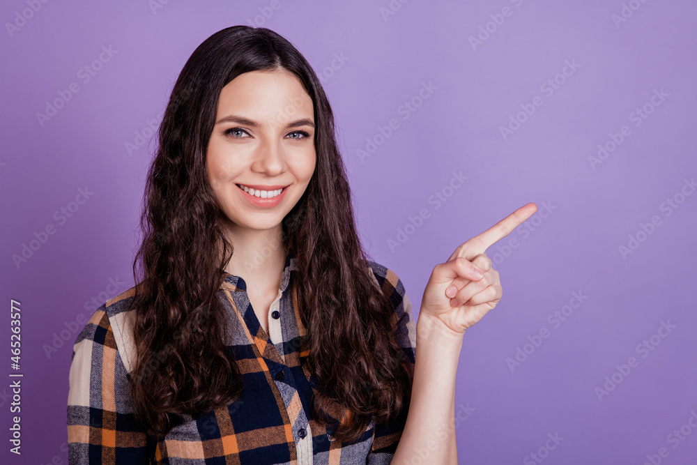 Young happy positive smiling woman suggest select advert point index finger empty space isolated on violet background Young happy positive smiling woman suggest select advert point index finger empty space isolated on violet background