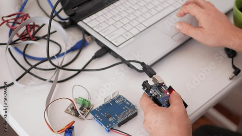 A male programmer creates robotics, an arduino board controls servo motors. DIY mechanics, programming through codes on a laptop. Technologies of the future. photo