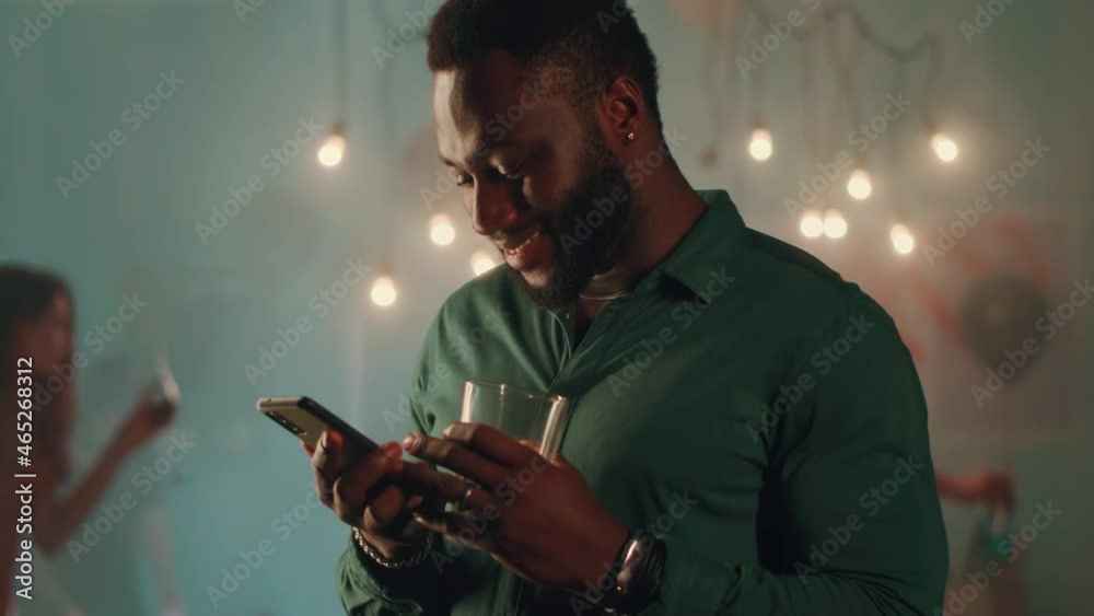 Glad black male communicating via text messages during party