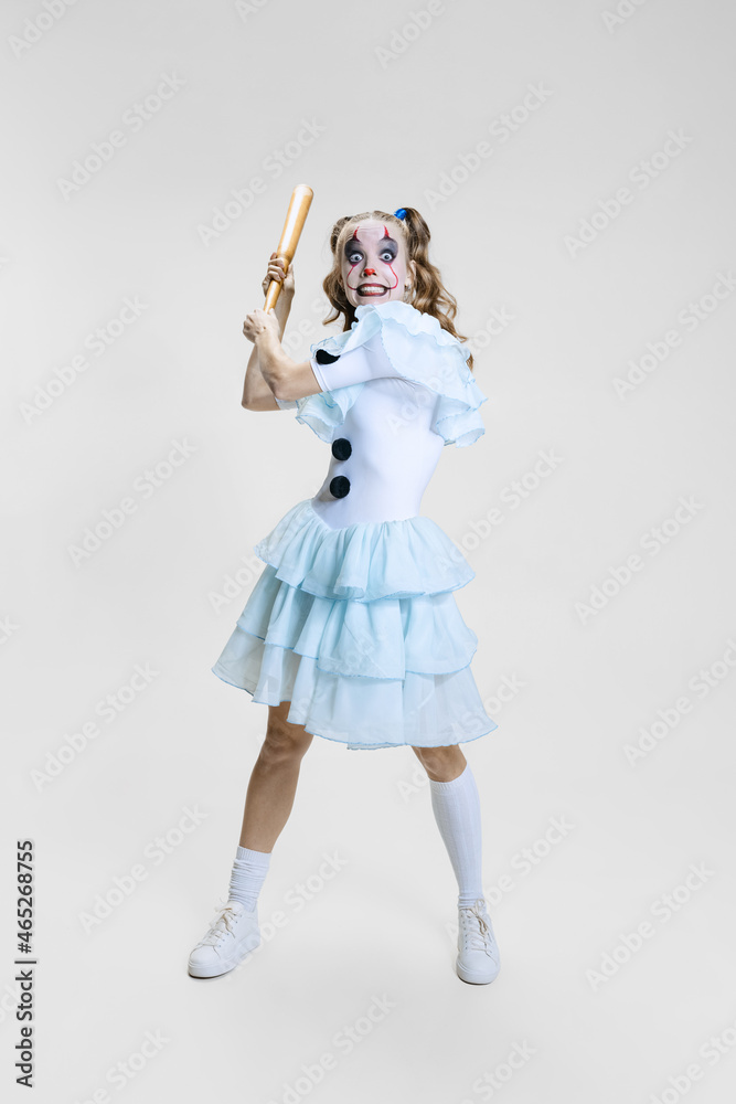 Halloween spooky theme. Portrait of beautiful artistic girl in halloween make-up and costume of dancing clown isolated over grey background Halloween spooky theme. Portrait of beautiful artistic girl in halloween make-up and costume of dancing clown isolated over grey background