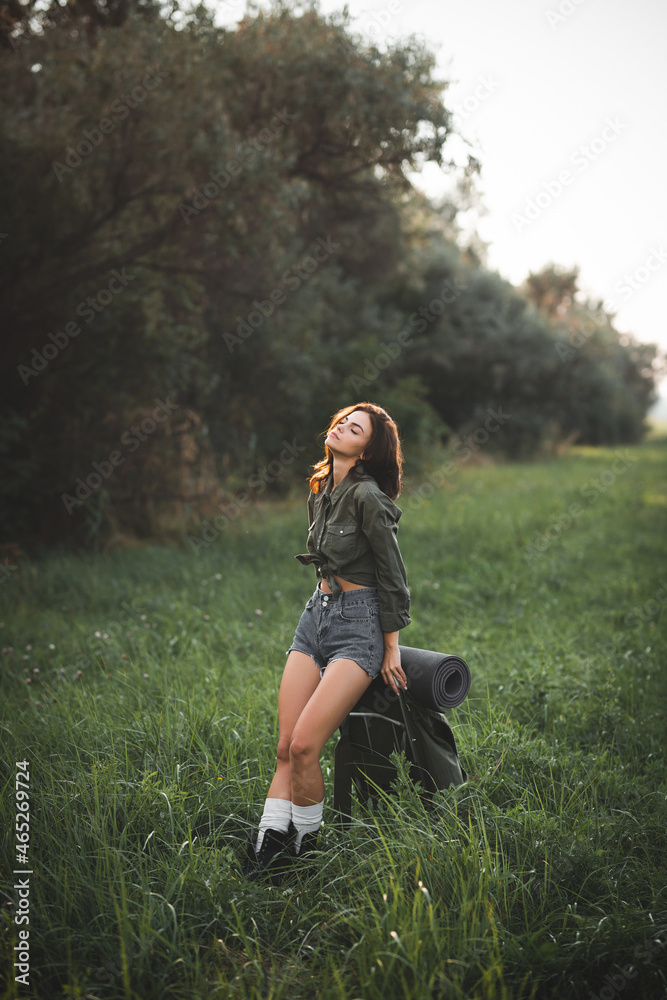 Hiking. A young girl with a retro backpack for hiking walks along a clearing road. Hitch-hiking Hiking. A young girl with a retro backpack for hiking walks along a clearing road. Hitch-hiking