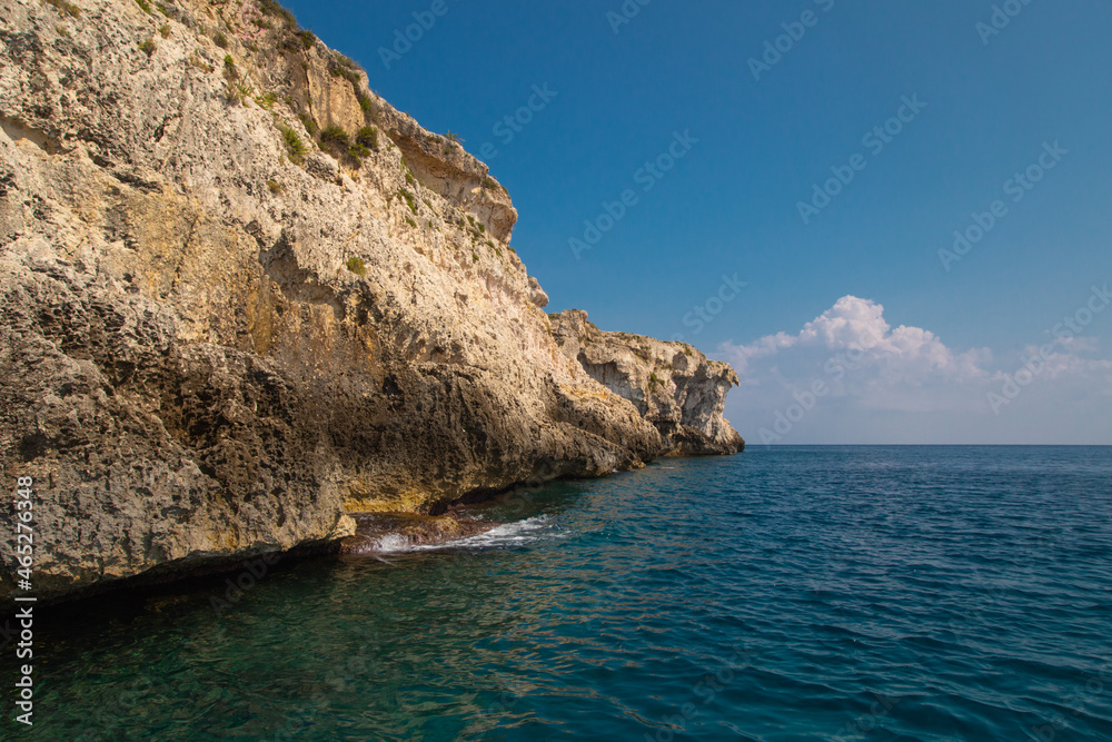 Sea side view of Siracusa coast cliffs, sandstone rocks and caves in sunny summer day. A bright colorful photo good for touristic booklet or book, boat trip ads, posters etc.