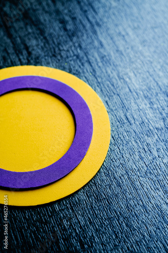 a circular intersex flag on a textured surface photo