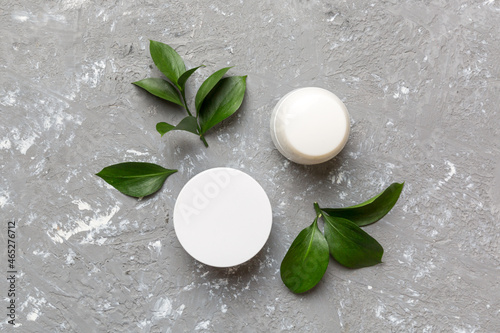 Organic cosmetic products with green leaves on cement background. Flat lay