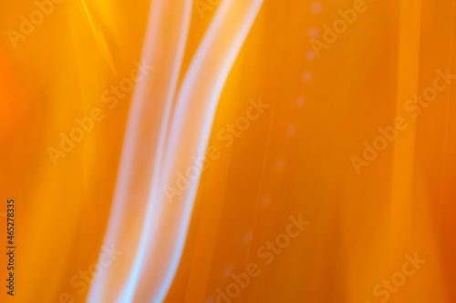 Abstract image of white light stripes running vertically across an orange background of moving lights