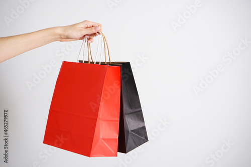 Paper black and red bag, eco packaging in a female hand on a white background. Space for text.