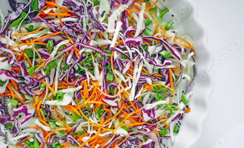Coleslaw cabbage salad with cabbage, carrots, herbs and sesame seeds on a white plate. Healthy eating, vegan food