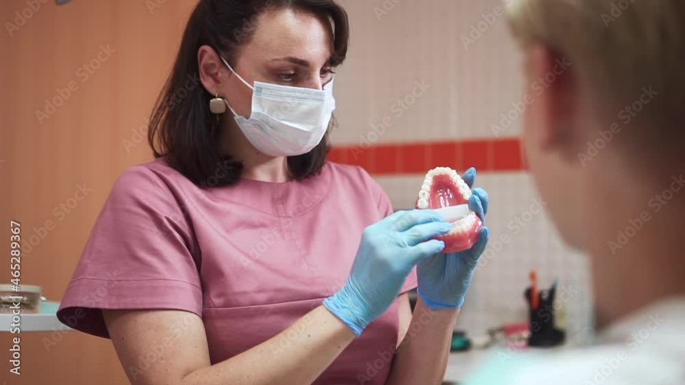 Orthodontist consults teenager patient. Skilled lady dentist with disposable mask puts aligner